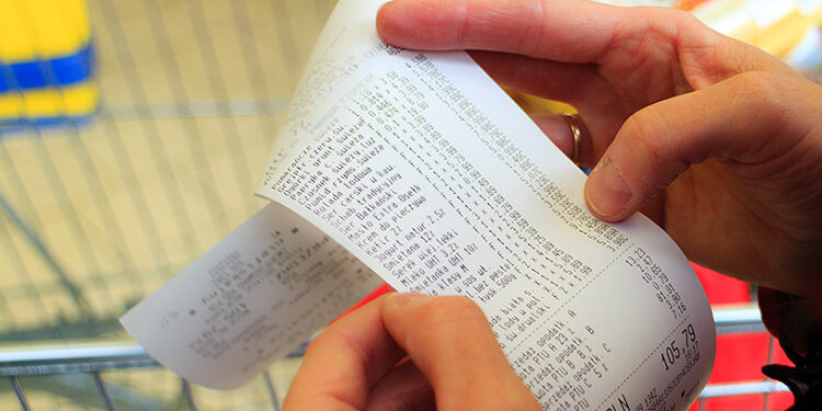Supermarket shop. Closeup of paper check receipt bill in human hand. Paying and retail.
** Note: Visible grain at 100%, best at smaller sizes